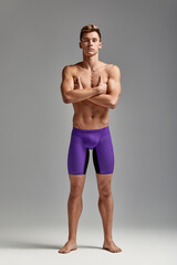 Fototapeta premium Young swimmer in excellent physical shape in full growth on a gray background with copy space, call for sports, advertising banner