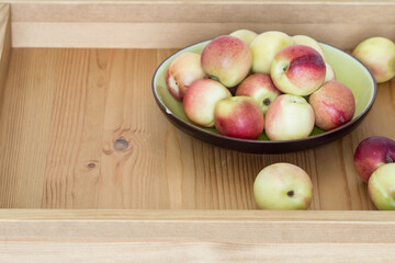 Ripe juicy nectarines on a round ceramic plate on a wooden tray. Selective focus.