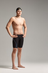 Fototapeta na wymiar Young swimmer in excellent physical shape in full growth on a gray background with copy space, call for sports, advertising banner