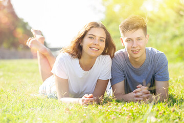 Young man and girl are lying on the grass together