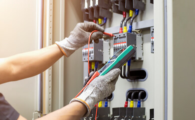 Electrical engineer tests the operation of the electric control cabinet on a regular basis for...
