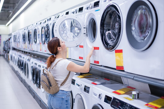 Caucasian woman chooses a washing machine in a home appliances store