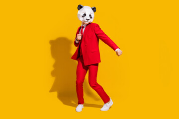 Photo of positive crazy panda guy enjoy dance wear mask red suit tie sneakers isolated on yellow...