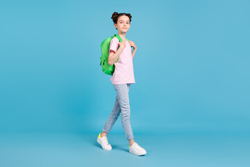 Photo of adorable shiny school girl wear pink t-shirt backpack smiling walking isolated blue color background