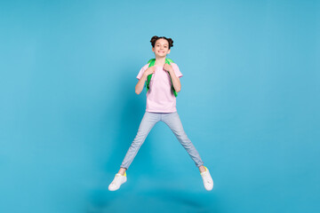 Photo of charming cute schoolgirl dressed pink t-shirt rucksack jumping high smiling isolated blue color background