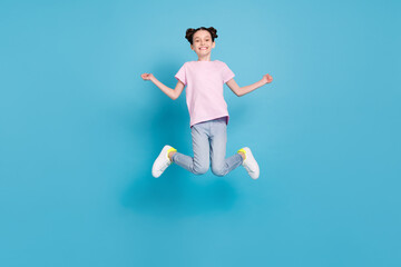 Fototapeta na wymiar Photo of adorable sweet schoolgirl dressed pink t-shirt jumping high smiling isolated blue color background
