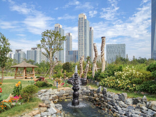 Skyline of Songdo in South Korea, wooden totem poles called jangseung in a park