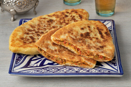Pair of traditional fresh baked whole and halved Moroccan stuffed batbot  on a plate close up 