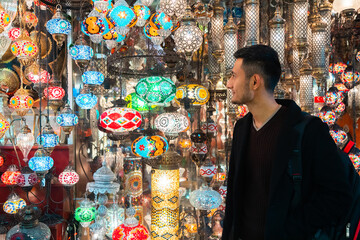 Young man looking at Turkish lamps for sale in the Grand Bazaar, Istanbul, Turkey
