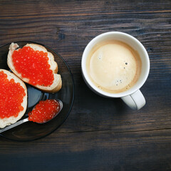 Coffee cup, sandwiches with red caviar and spoon. Top view. Flat lay.