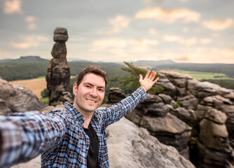 Glücklicher junger Mann mache ein Selfie auf den Berggipfel in der Sächsischen Schweiz
