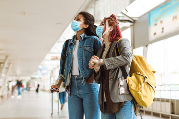 Fototapeta premium Multiracial two women in face masks standing at train station