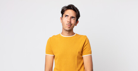 hispanic handsome man looking puzzled and confused, wondering or trying to solve a problem or...