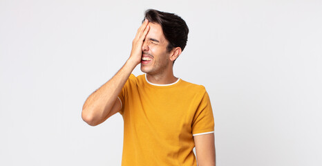 hispanic handsome man laughing and slapping forehead like saying d’oh! I forgot or that was a...