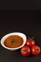 Fresh vegetables and dried veggie powder. Tomato on dark paper background. Vegetarian healthy detox food.