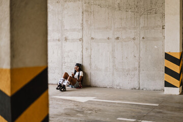 Black young woman using mobile phone while sitting on floor