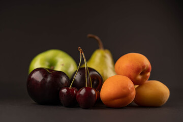 Fresh fruits and dried fruit powder. Pear, apple, apricot, cherry, currant, strawberry and plum on dark paper background. Vegetarian healthy detox food.