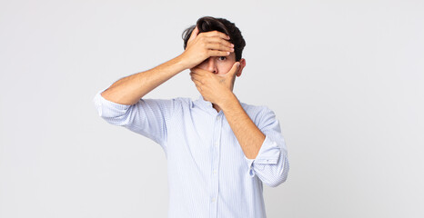 hispanic handsome man covering face with both hands saying no to the camera! refusing pictures or...