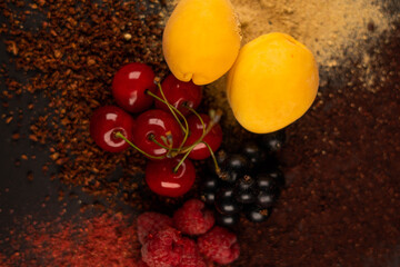 Fresh fruits and dried fruit powder. Apricot, cherry, currant and raspberries  on dark paper background. Vegetarian healthy detox food.