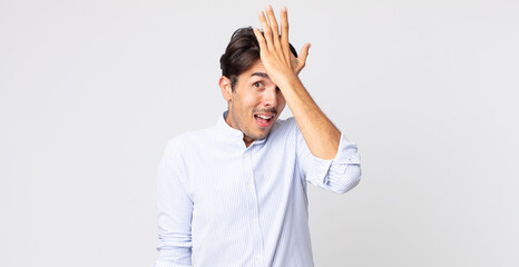 hispanic handsome man raising palm to forehead thinking oops, after making a stupid mistake or...