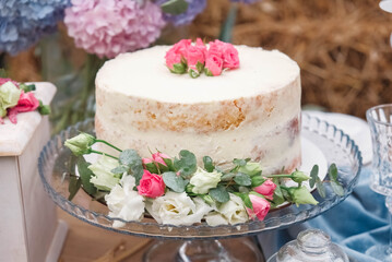 White wedding cake decorated by flowers standing of festive table. Copy, empty space for text
