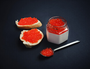 Still life with red caviar. Sandwiches with red caviar, glass jar and spoon.