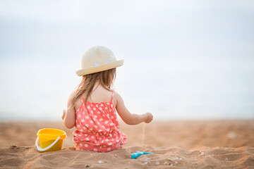 baby girl is sitting on beach and playing in sand in summer. holidays with children
