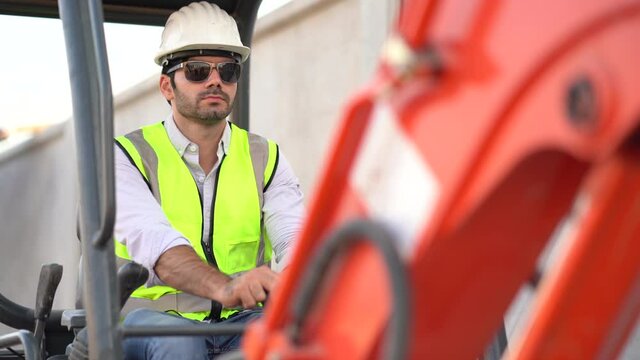 construction worker driving excavator on site .