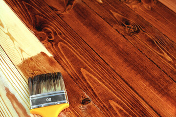 Wood staining diy. Brush. Painting wooden patio deck with protective brown oak varnish. Outdoor...