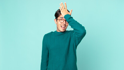 hispanic handsome man raising palm to forehead thinking oops, after making a stupid mistake or...