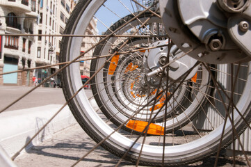 Lots of bicycle wheels with vanishing point in a center of city