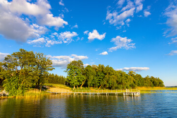 Panoramic summer view of Jezioro Selmet Wielki lake landscape with vintage pier reeds and wooded shoreline in Sedki village in Masuria region of Poland
