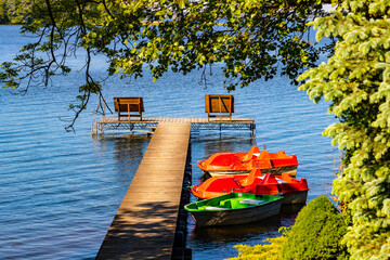 Panoramic summer view of Jezioro Selmet Wielki lake landscape with boat pier and wooded island in Sedki village in Masuria region of Poland - obrazy, fototapety, plakaty