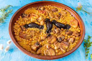 Baked rice in clay pot on a blue background. Typical dish of Valencian gastronomy.
