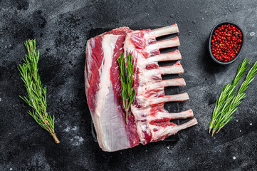 Raw fresh rack of lamb meat on marble board. Black background. Top view