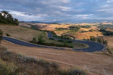 Tuscany landscape with winding road and green rolling hills near Volterra