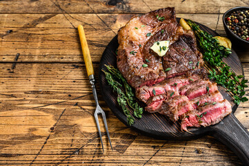 Roast rib eye beef meat steak on a cutting board. wooden background. Top view. Copy space