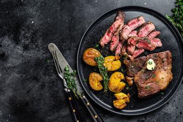 Cut Grilled rib eye beef meat steak with potato. Black background. Top view. Copy space