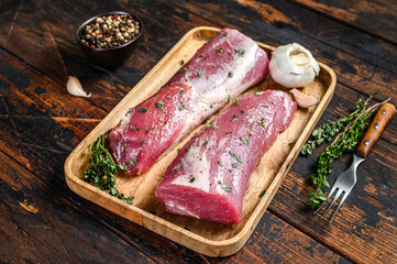 Marinated pork tenderloin meat steak with thyme. Dark wooden background. Top view