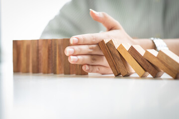 Close up of hand stopping wooden domino business crisis effect or risk business protection concept,
