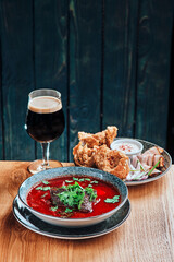 Homemade Russian, Ukrainian and Polish national soup - red borscht made of beetroot, vegetables and meat. Beer snack on background. High quality photo