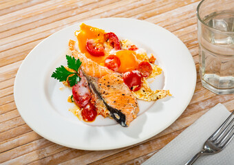 Dish of tasty scrambled eggs with salmon and tomatoes at plate on table