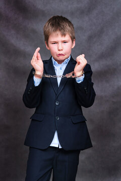 A Boy In Handcuffs On His Hands, Copy Space On A Black Studio Background