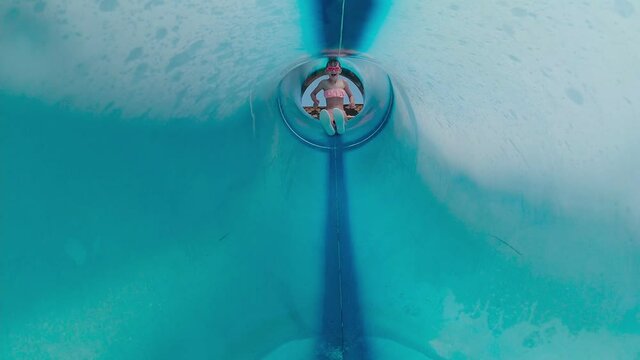 Girl in water tube slide splashing water slow motion