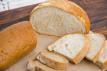 delicious white wheat and rye bread on parchment and a wooden table. the concept of gluten-free and food products, baking