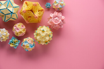 Set of multicolor handmade modular origami balls or Kusudama Isolated on pink background. Visual...