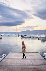 Fototapeta premium Tourism concept. Young traveling woman enjoying the view at sea marina.