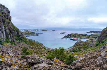 Fototapeta na wymiar View from above from a cliff on the ocean and on blue panorama of mountains and Reine in Lofoten islands, Norway