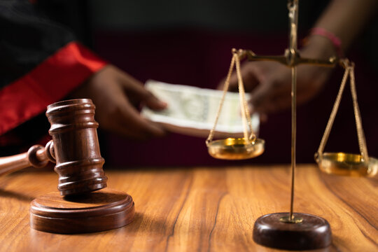 Focus on gavel, concept of judicial corruption showing by judge taking money in background by making deal.