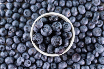 Blueberries in a cup on blueberry layer background